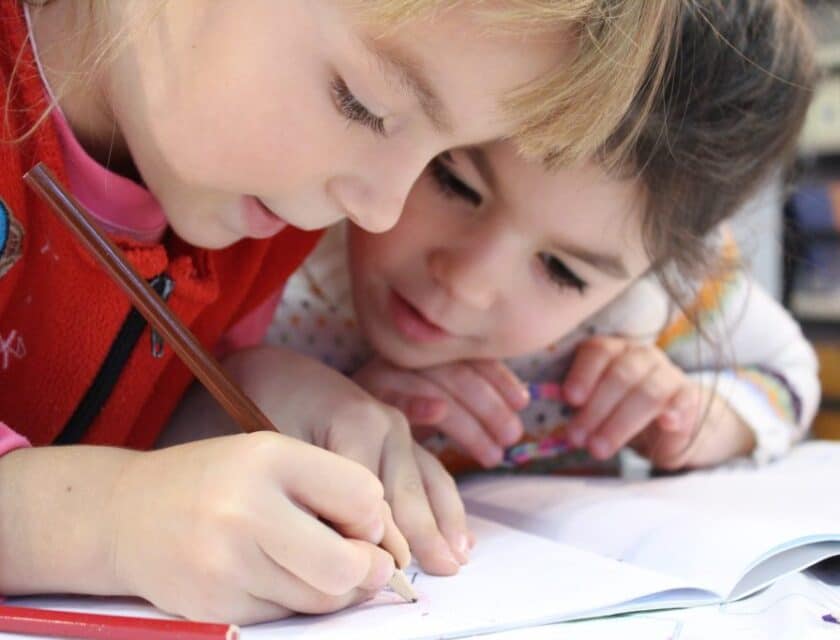 Two girls use colored pencils at a child care center.